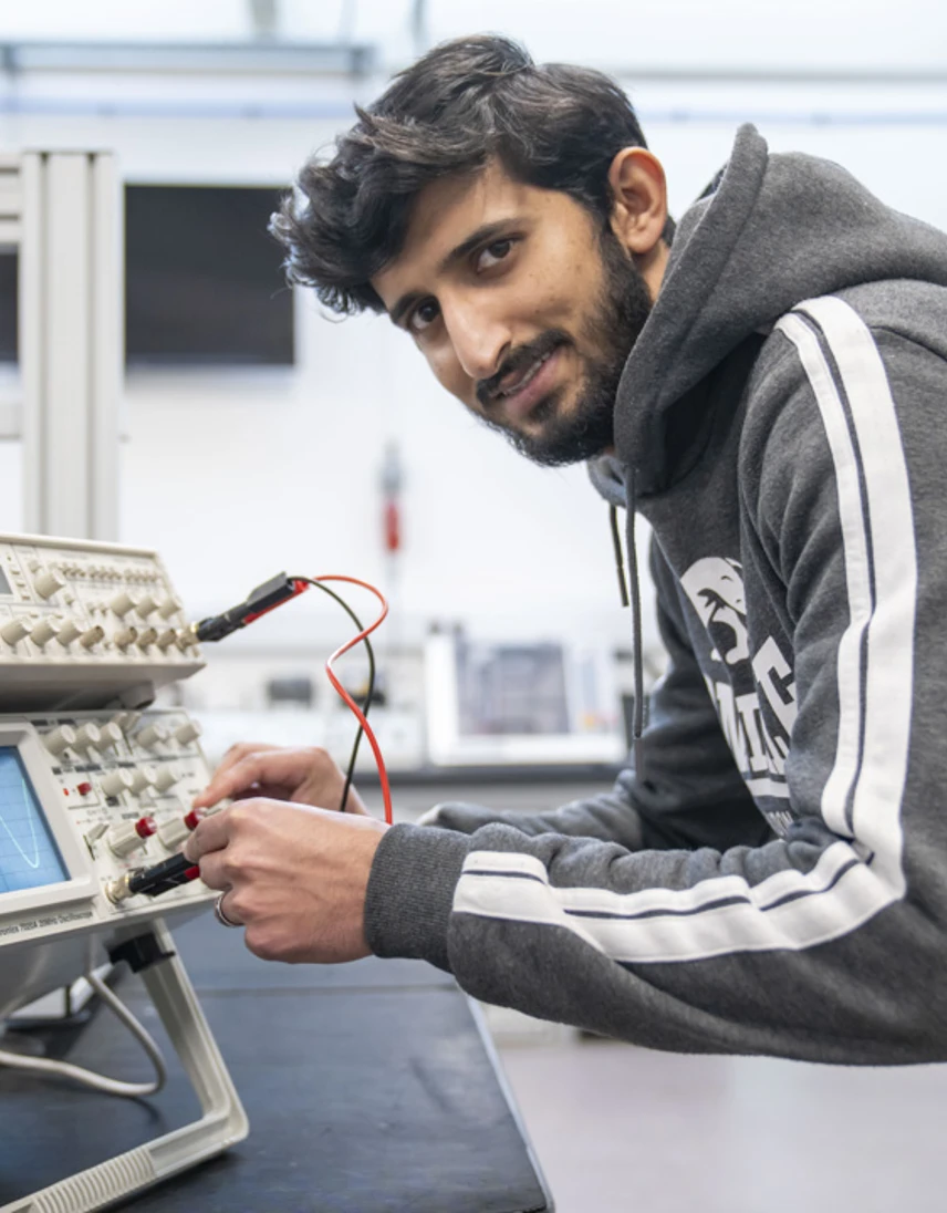 Student testing an oscilloscope, adjusting probes and controls to analyze electronic signals in a hands-on engineering session. Student testing an oscilloscope, adjusting probes and controls to analyze electronic signals in a hands-on engineering session.